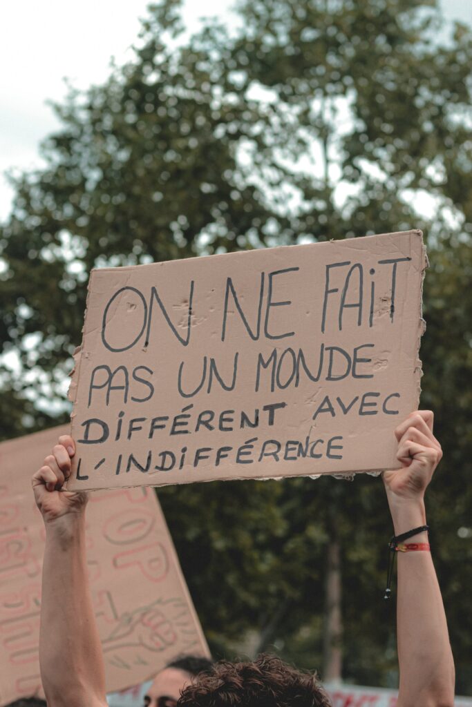 Carton de manifestant indiquant "On ne fait pas un monde différent avec l'indifférence"